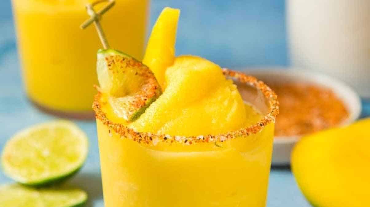 A refreshing mango margarita with a salted rim and garnished with lime and mango slice.