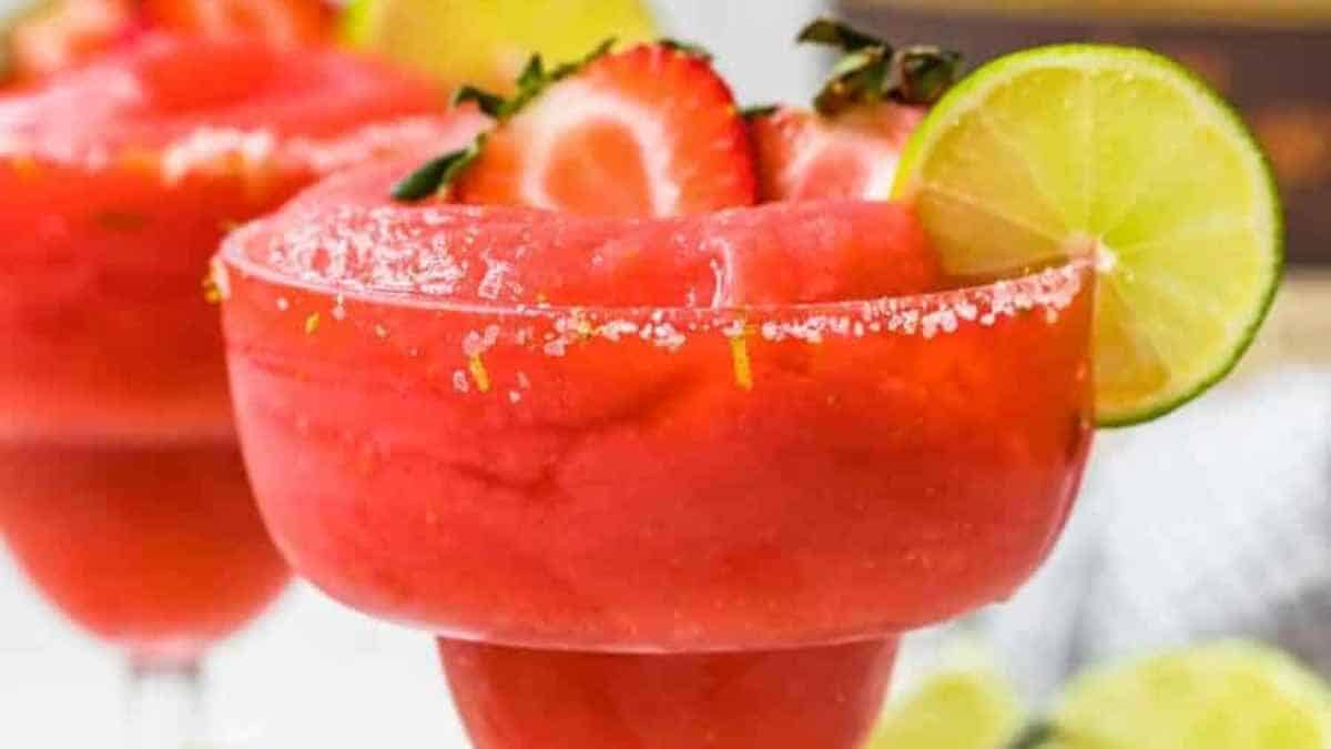 A refreshing frozen strawberry margarita garnished with a lime wheel.
