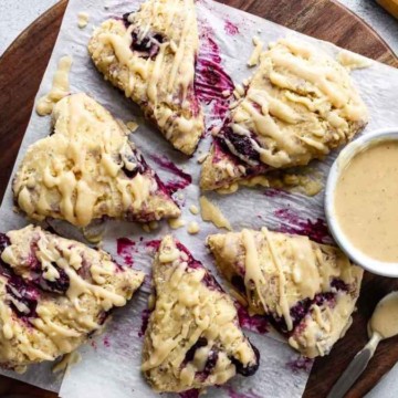 Scones with blueberry sauce on a wooden cutting board.