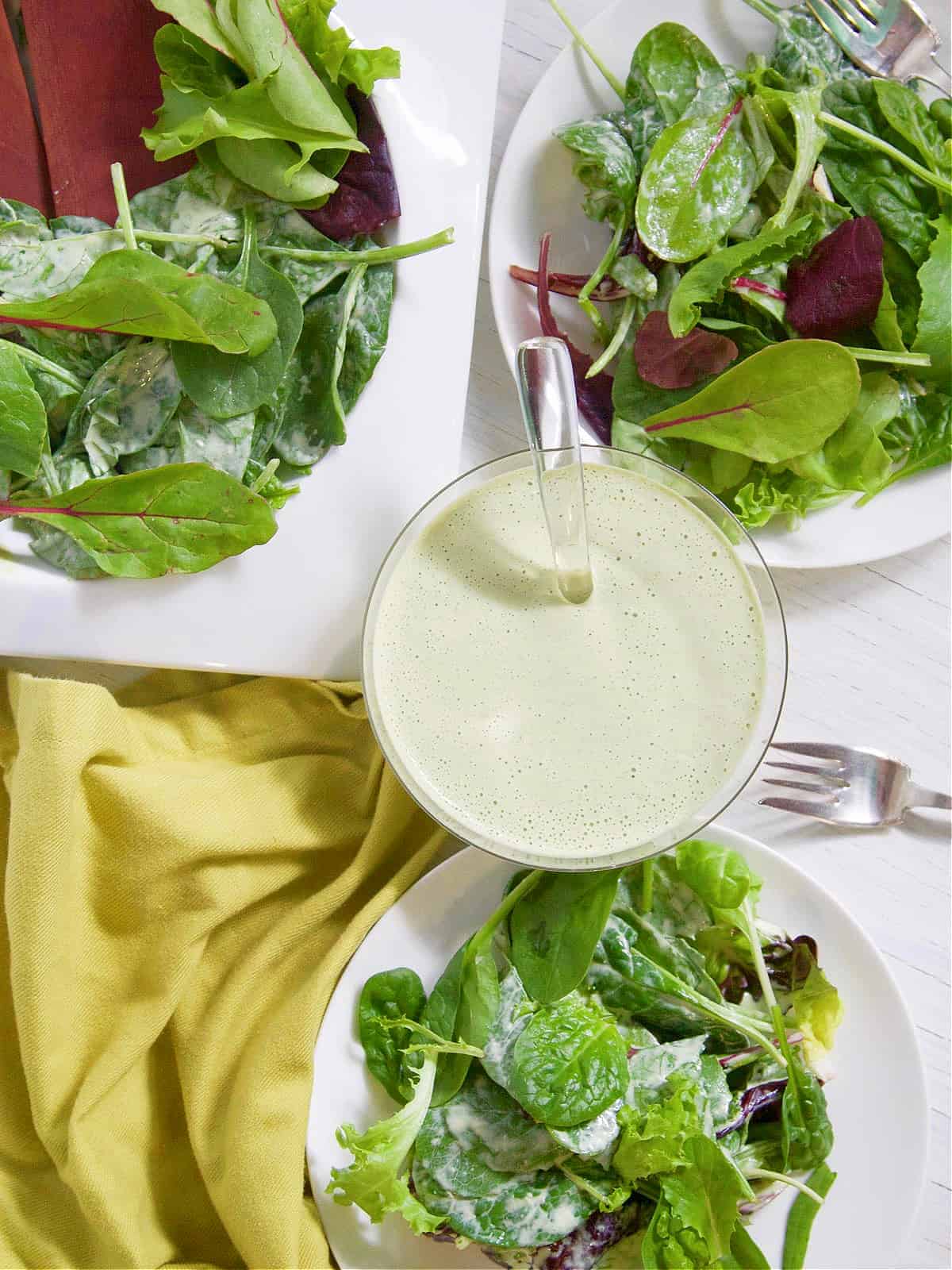 A salad with dressing on a white plate, perfect for a Vitamix enthusiast.