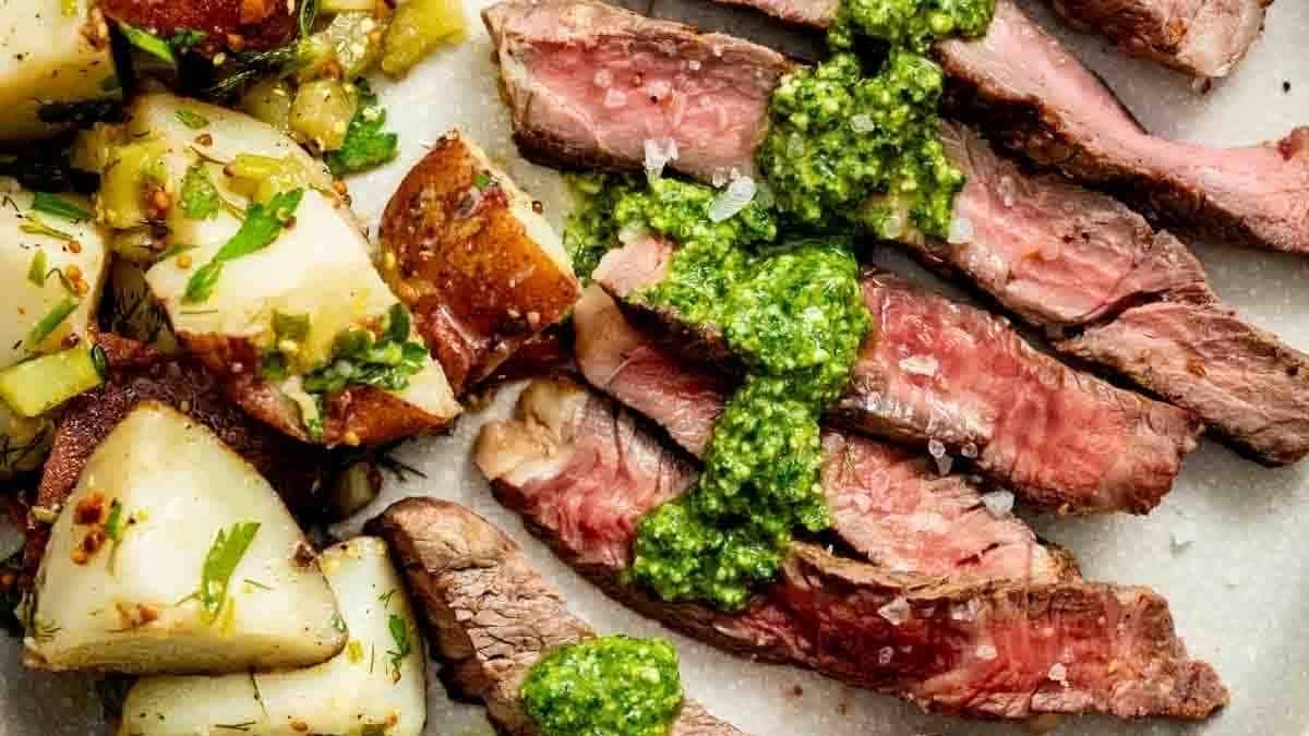 Steak with pesto and potatoes on a plate.