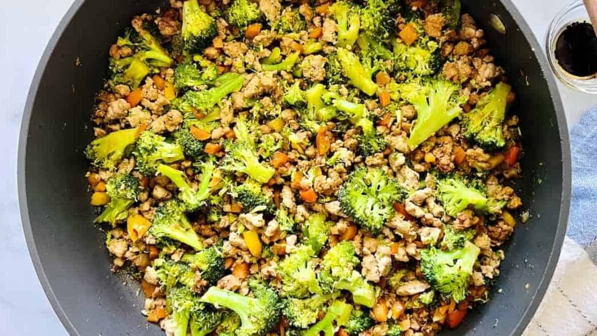 Stir-fried ground meat with broccoli and carrots in a cooking pan.