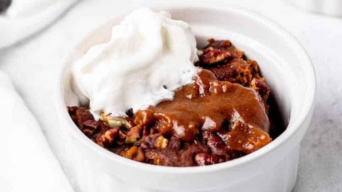 A bowl of warm dessert topped with whipped cream.