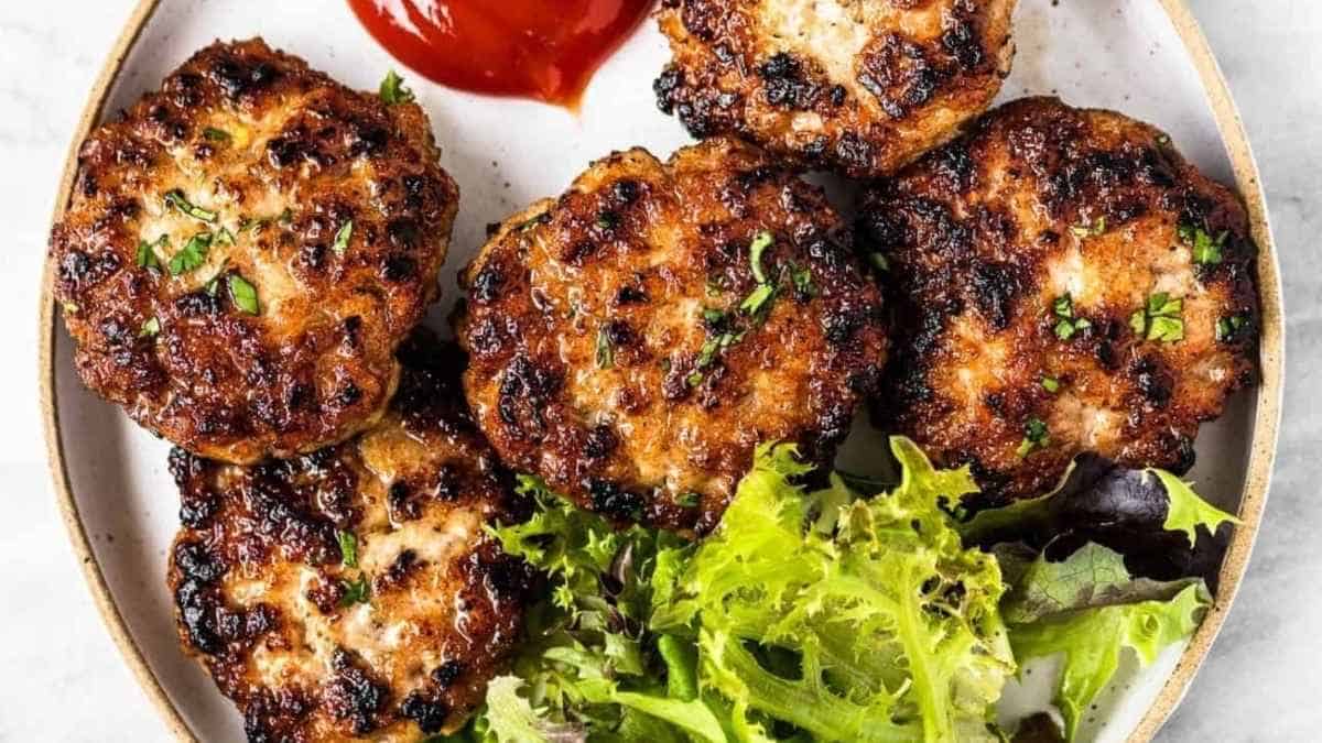 Grilled chicken burgers on a plate with salad and ketchup.