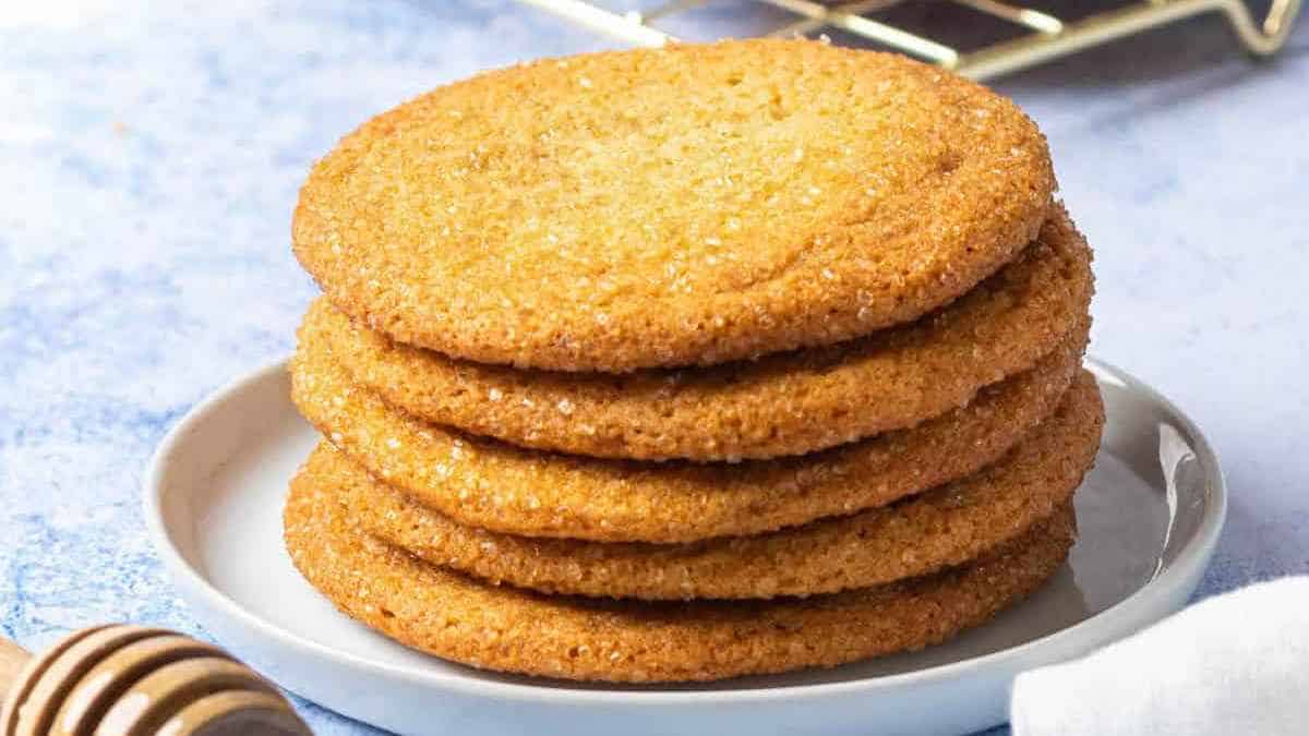 A stack of crispy golden-brown sugar cookies on a white plate.