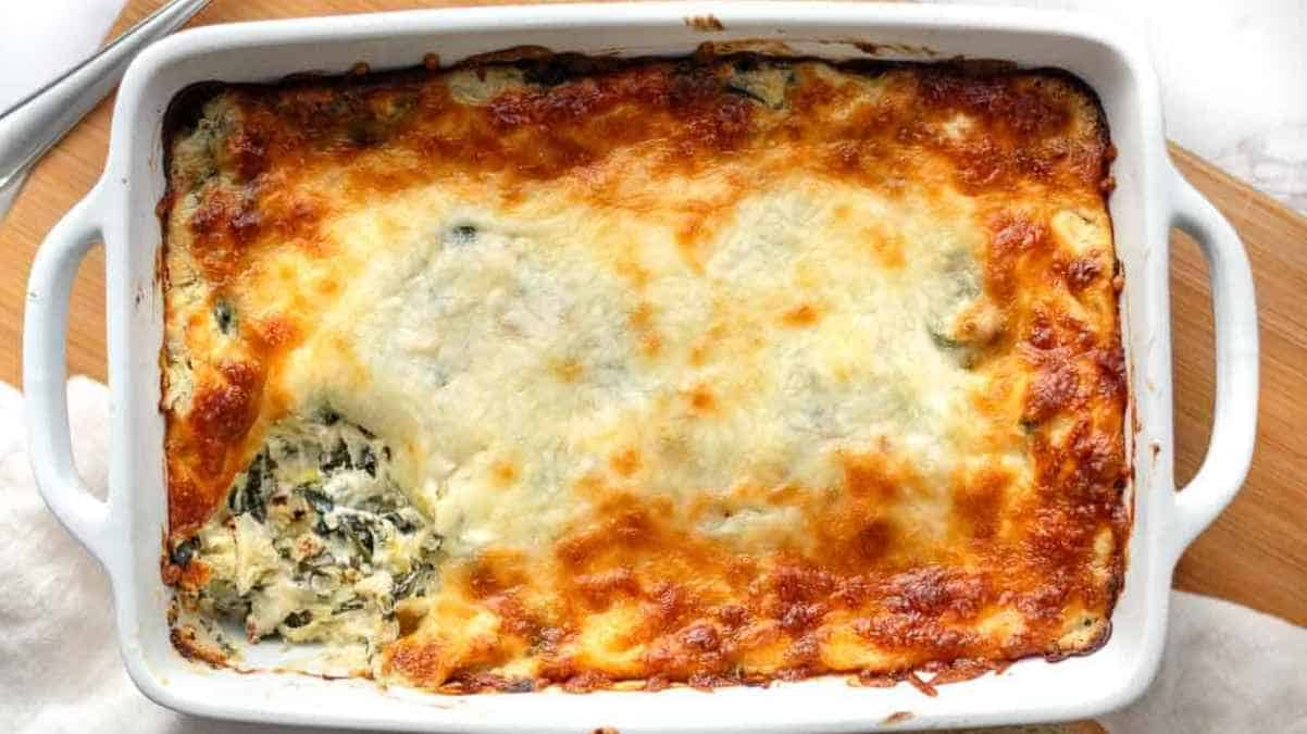 Golden-brown cheesy spinach lasagna in a white baking dish.