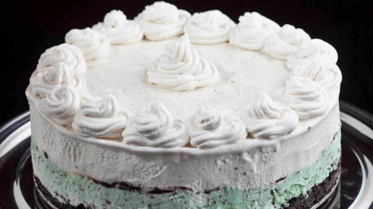 A round mint-flavored cake with white frosting and decorative swirls on top.