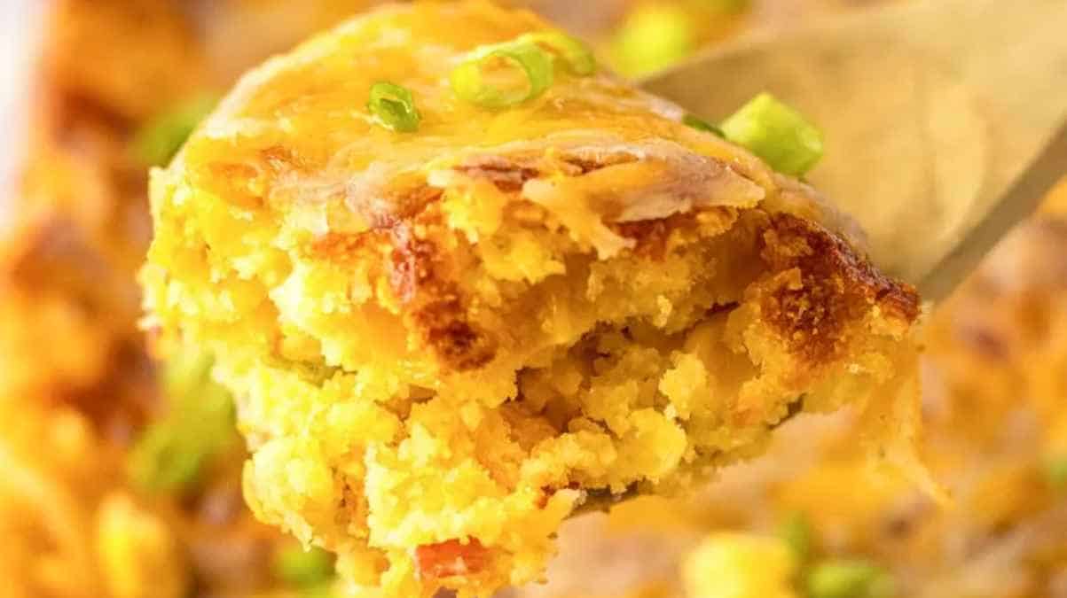 A close-up of a fork lifting a portion of a savory baked casserole, with visible green onions.