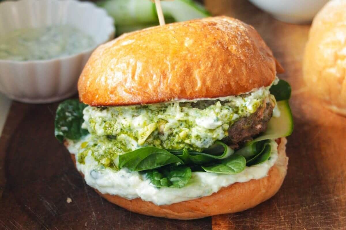 A gourmet burger with a beef patty, spinach, and herb aioli on a brioche bun.