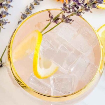 A pink drink with lemon slices and lavender flowers.
