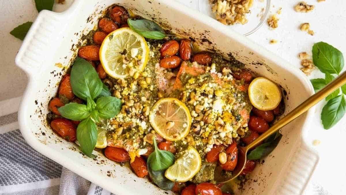 A baking dish with salmon, tomatoes and basil.