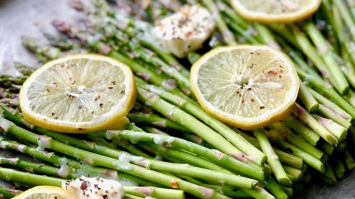 Fresh asparagus topped with lemon slices and seasonings.