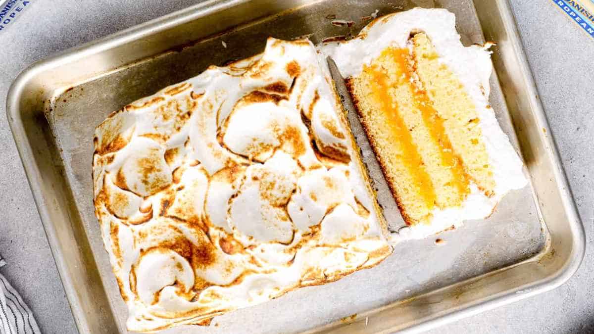 A slice of lemon meringue cake on a baking tray.