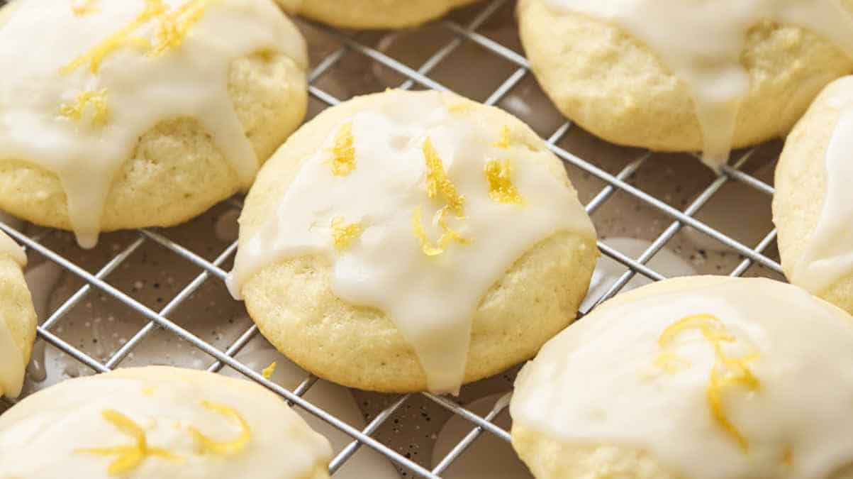 Freshly glazed lemon cookies on a cooling rack.