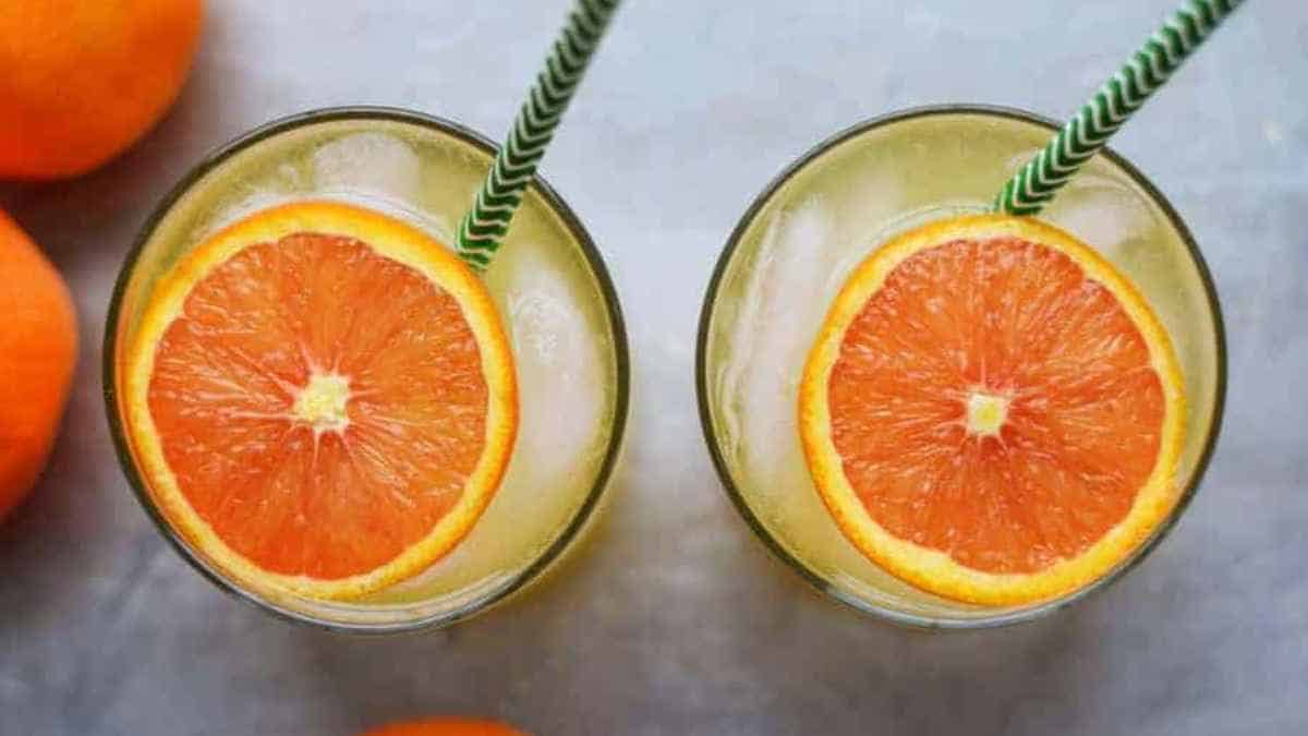 Two glasses of orange juice with straws.