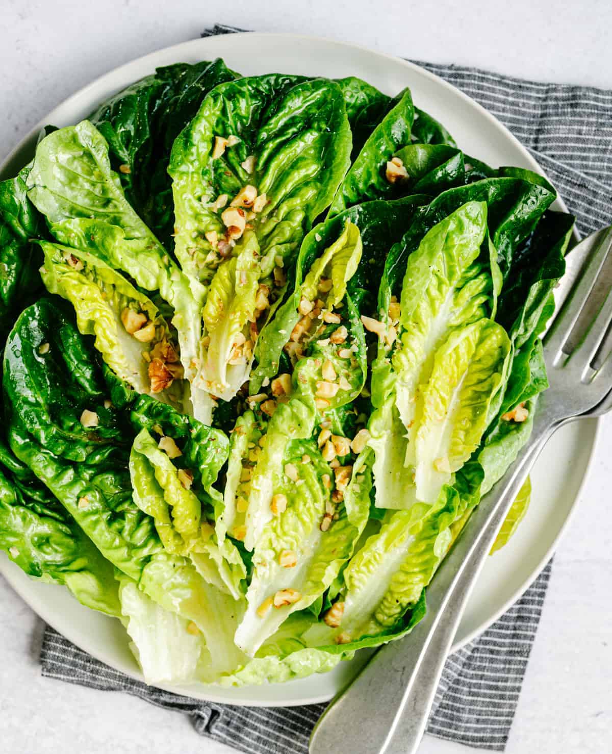 Little Gem Salad served on a round white platter and photographed from overhead. 
