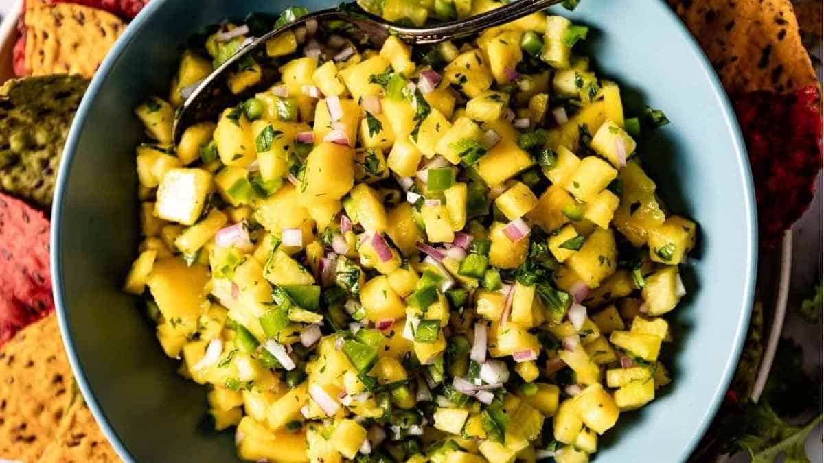 A bowl of mango salsa with a spoon.