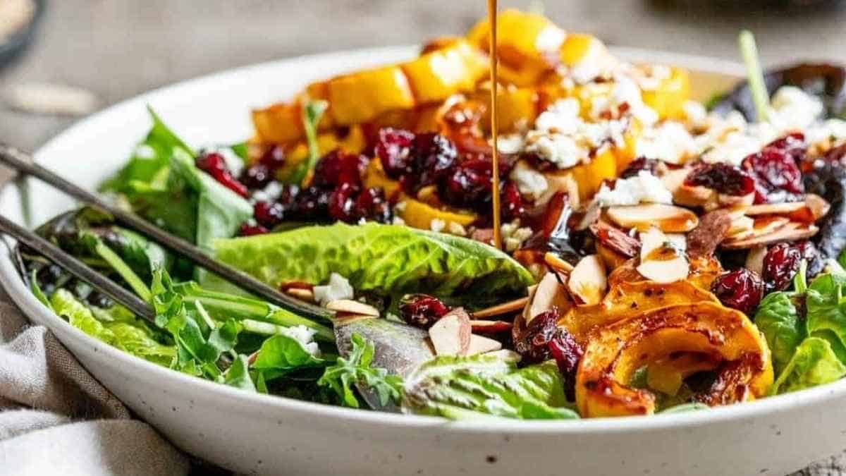 A bowl of salad with cranberries and walnuts.