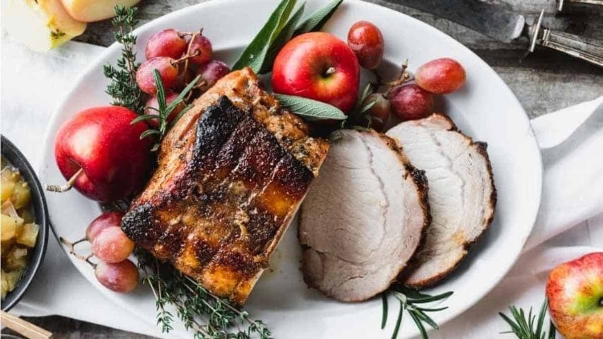 Pork tenderloin with apples and grapes on a plate.