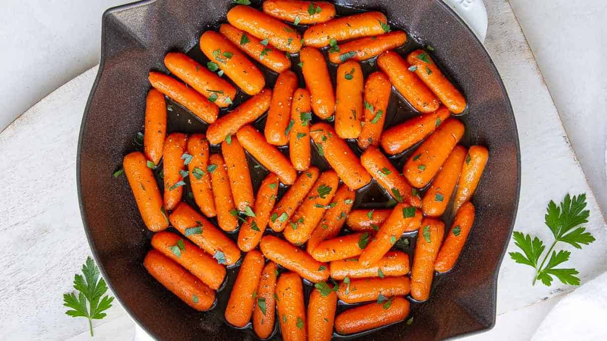 Roasted baby carrots garnished with parsley in a pan.