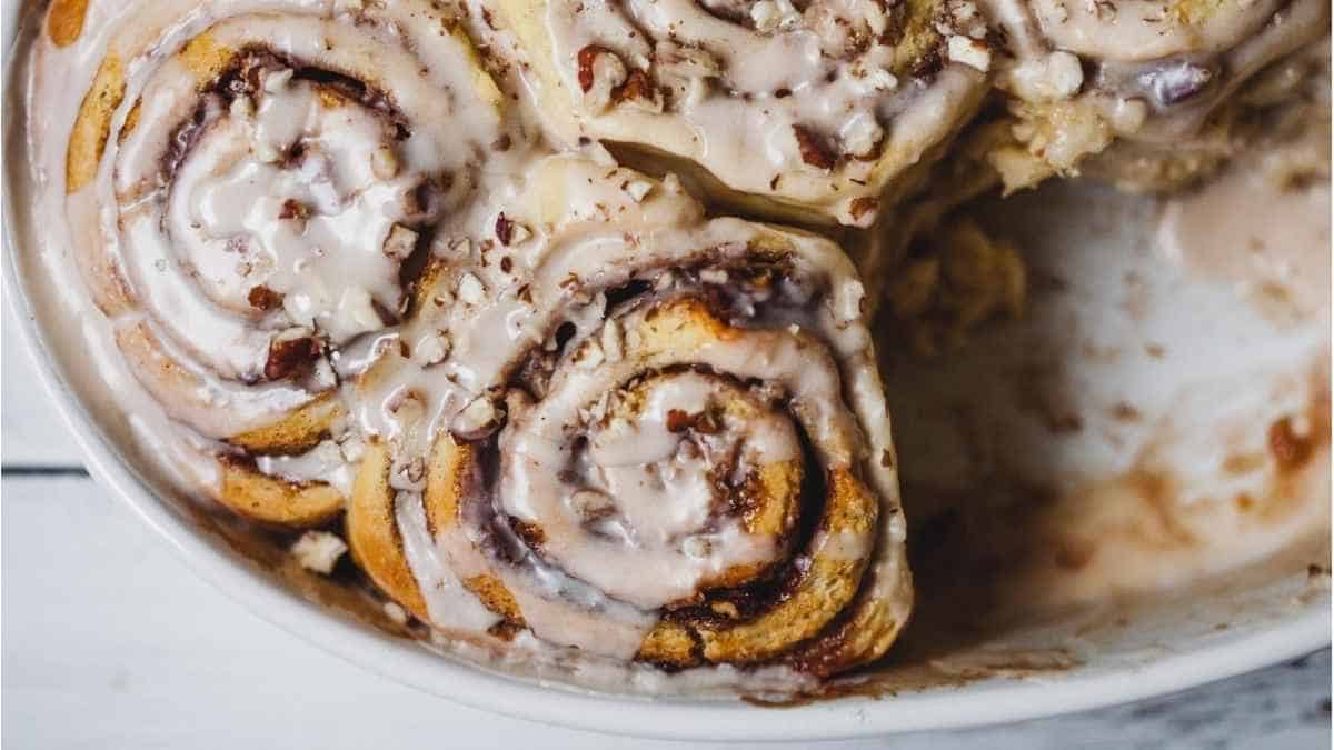 Cinnamon rolls in a white bowl with icing on top.