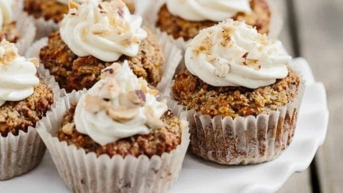 Carrot cupcakes topped with whipped cream and nuts.