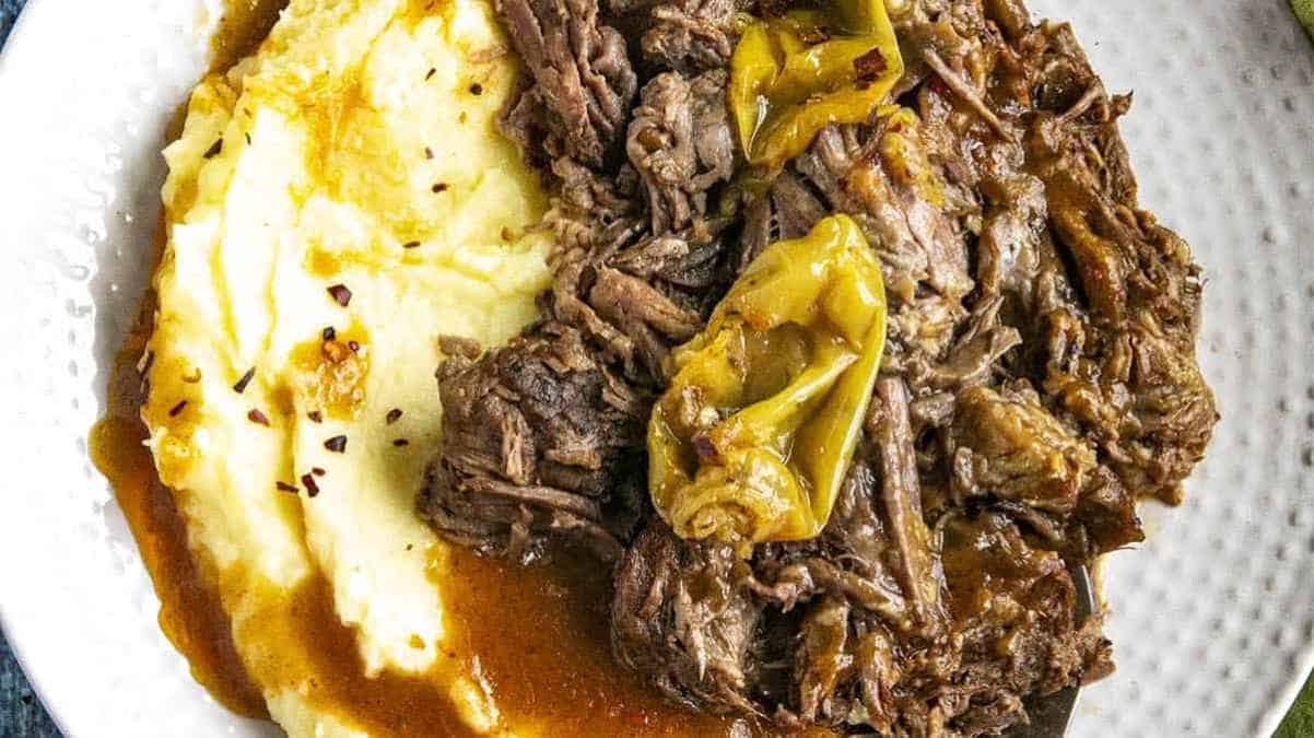 Pot roast with mashed potatoes and gravy on a plate.