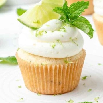 Cupcakes topped with whipped cream and mint leaves.