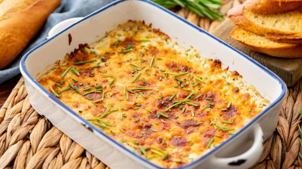 A freshly baked shepherd's pie garnished with chives in a white casserole dish, accompanied by bread slices.