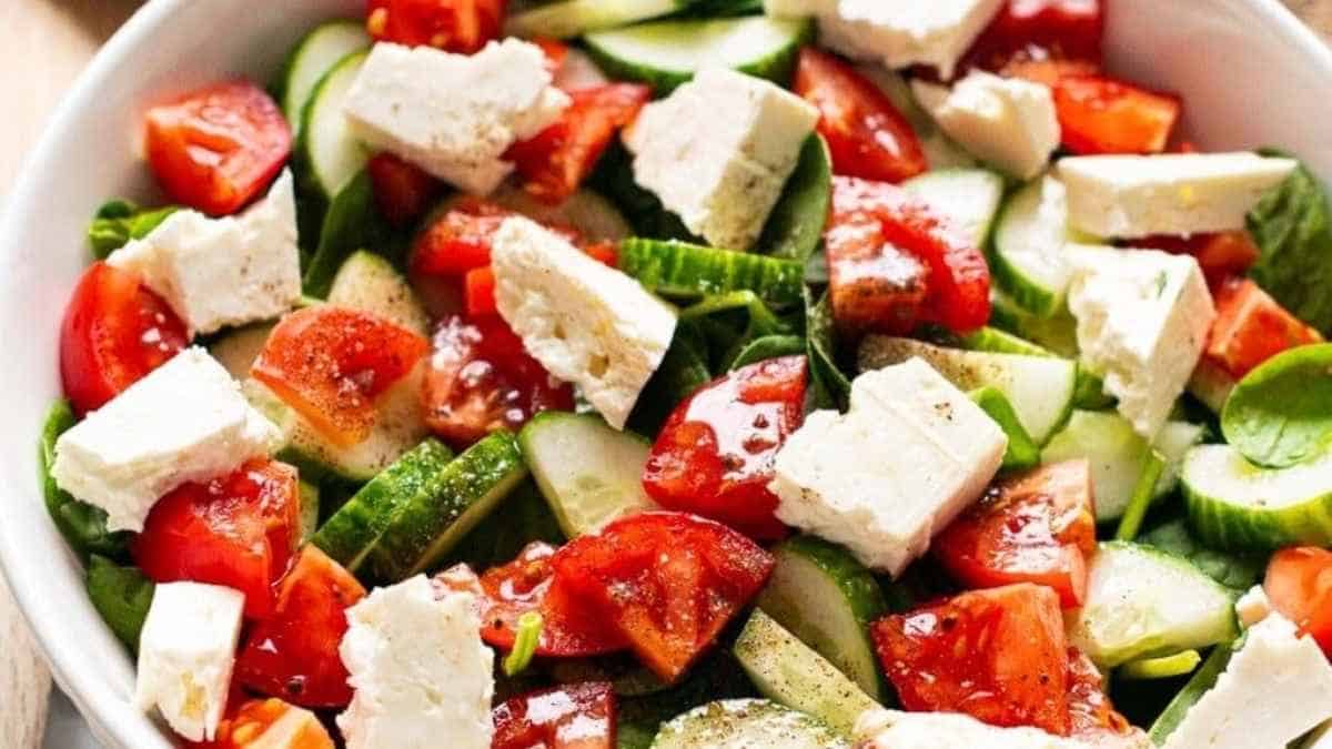 A bowl of salad with tomatoes, cucumbers and feta cheese.