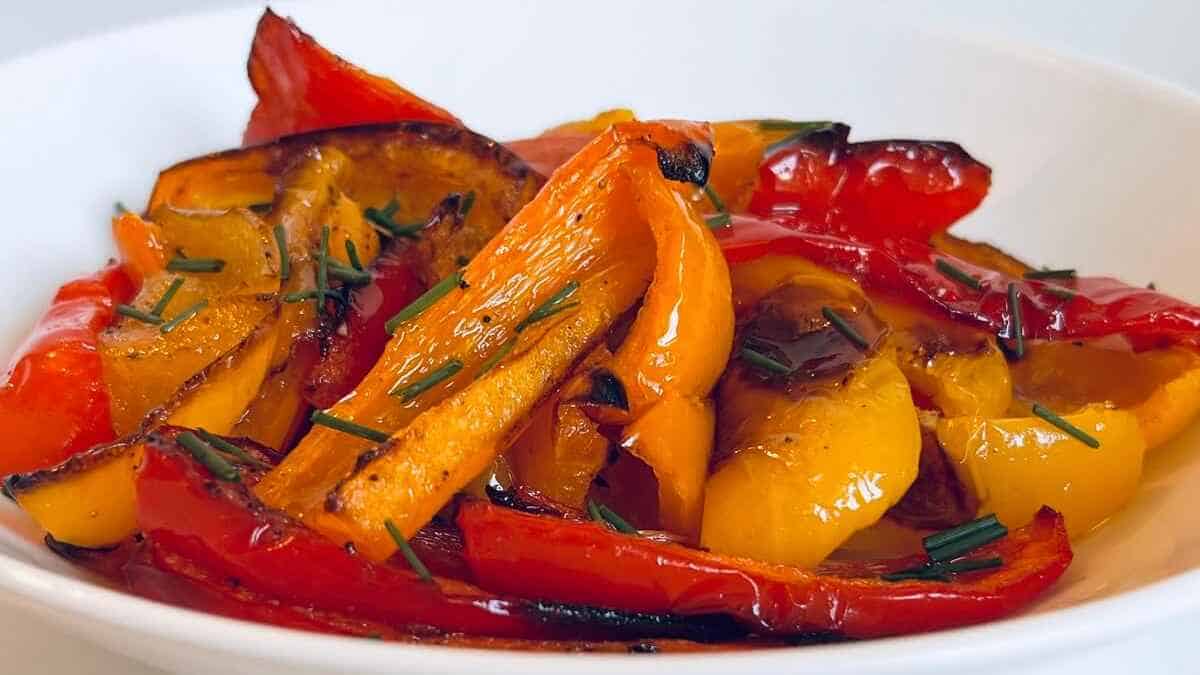 Roasted bell peppers seasoned with herbs in a white bowl.