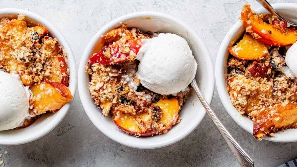 Three bowls of peach crisp with ice cream.