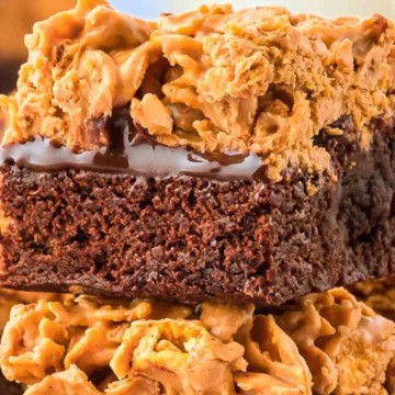 A chocolate brownie topped with a layer of peanut butter and crunchy cereal.