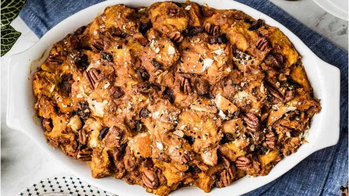 Pumpkin bread pudding in a white dish with pecans.