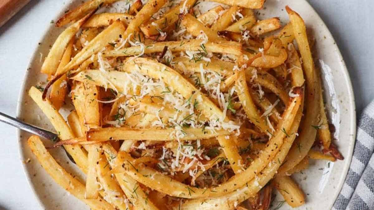 A plate of seasoned french fries sprinkled with grated cheese and herbs.