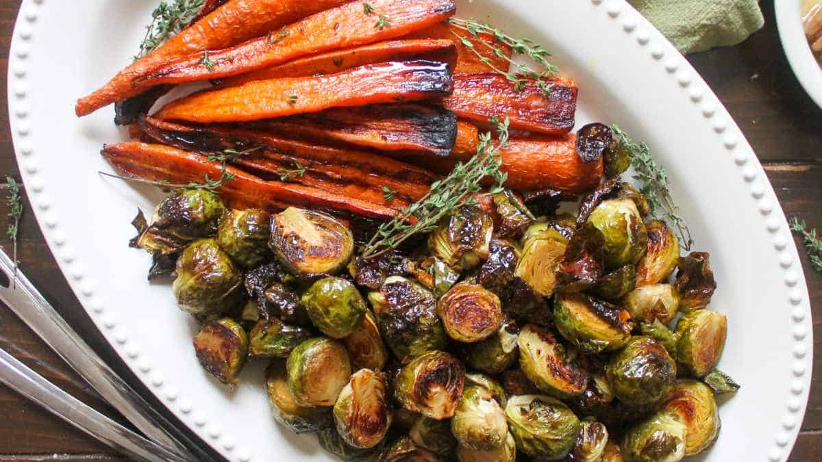 A plate of roasted carrots and brussels sprouts garnished with thyme.