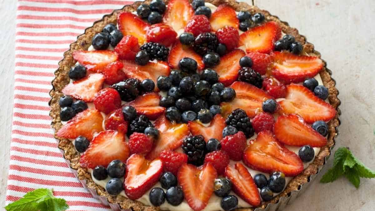 A fruit pie with cream and berries.