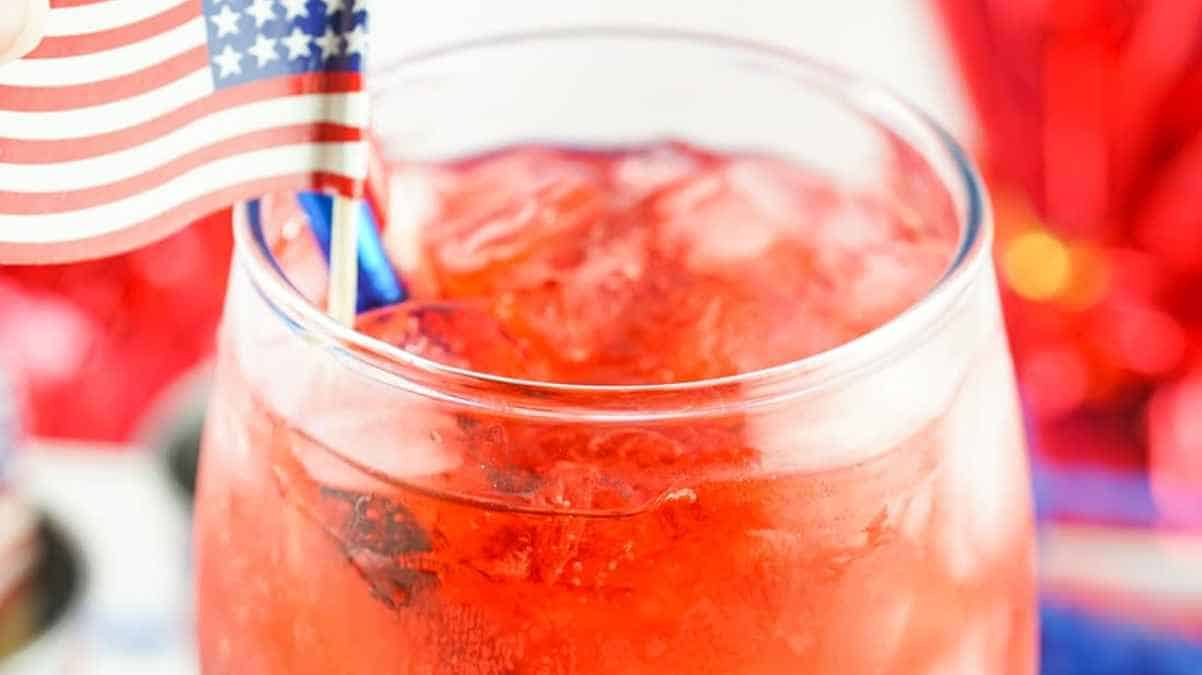 A close-up of a refreshing drink with ice in a glass garnished with an american flag.