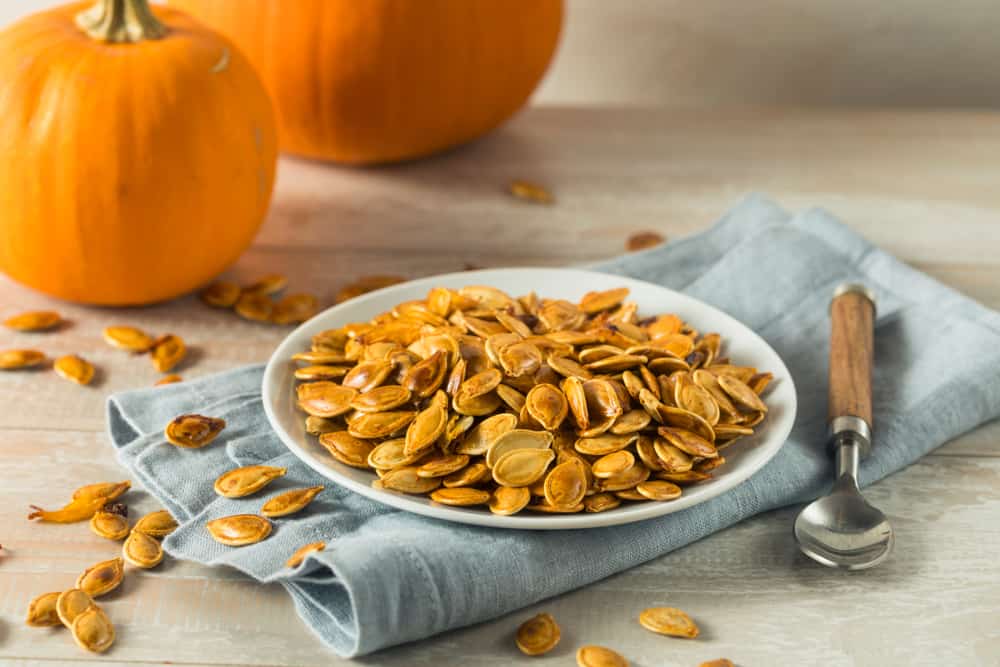 Roasted pumpkin seeds in a bowl on a table.