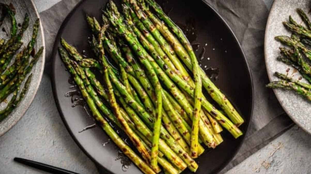 Grilled asparagus on a black plate.