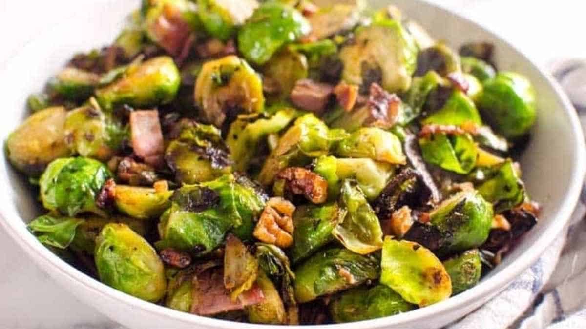 Brussel sprouts with bacon and walnuts in a white bowl.
