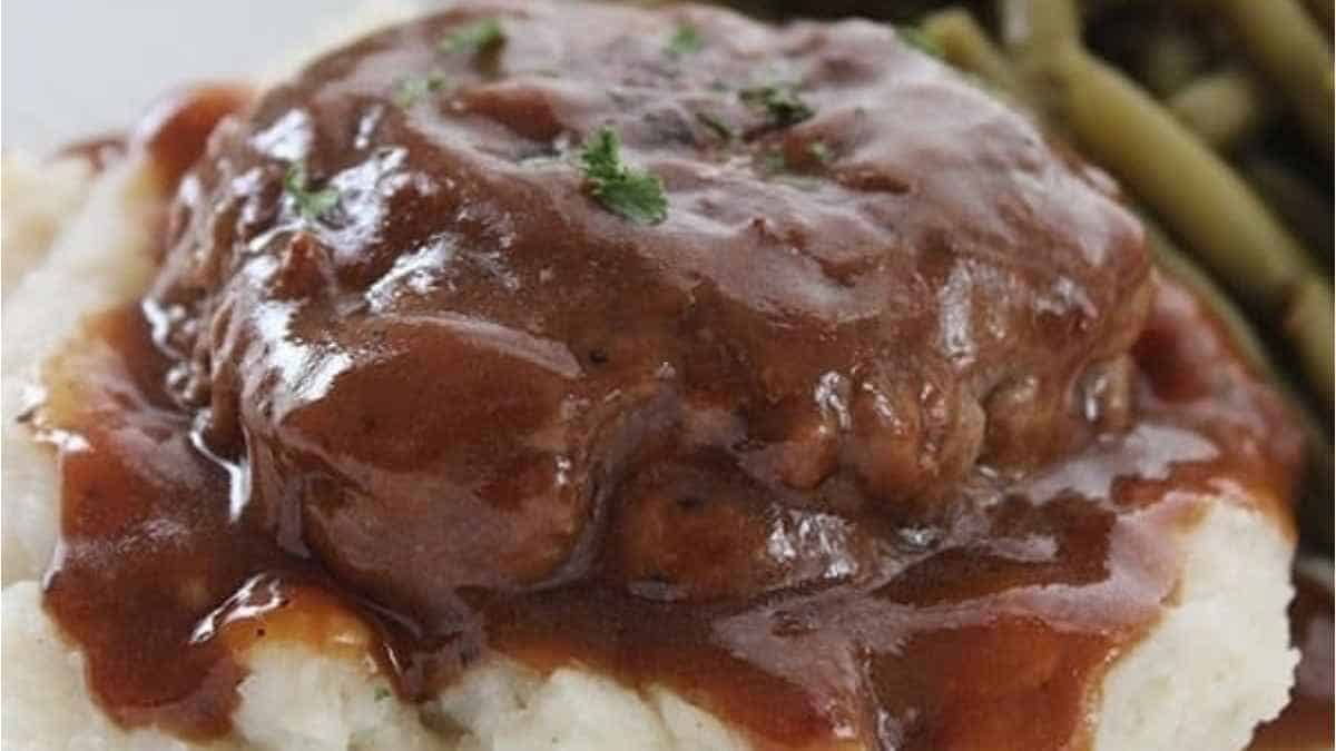 Meatloaf with gravy and green beans on a plate.