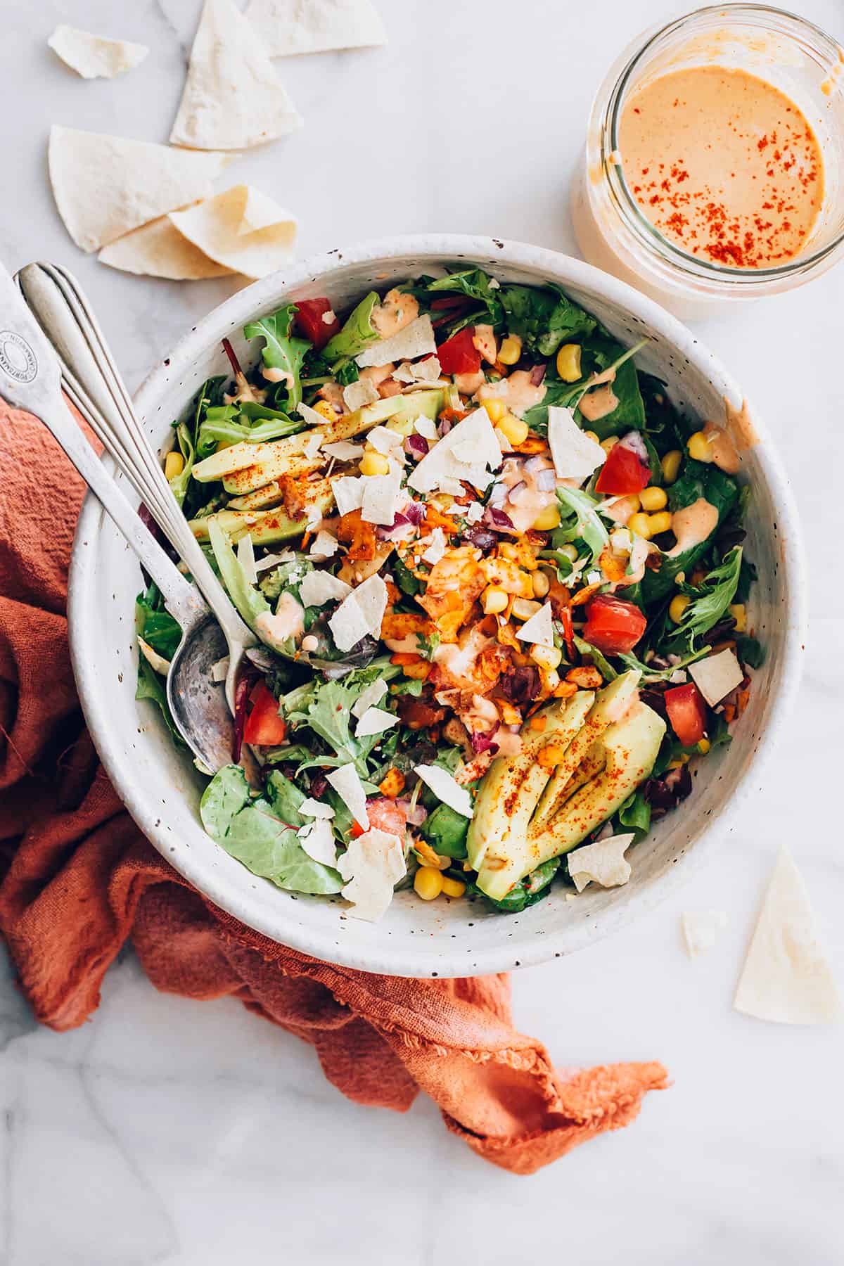 A bowl of gluten-free salad with a spoon and a fork.