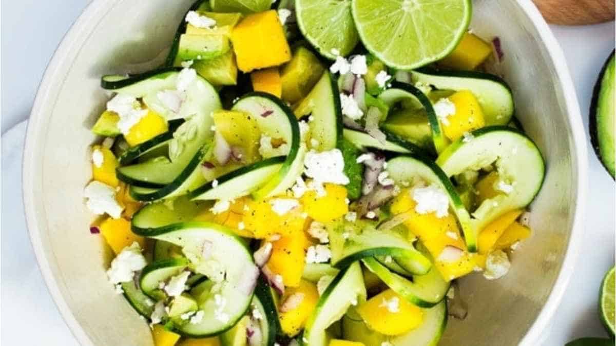 Mango and cucumber salad in a white bowl.