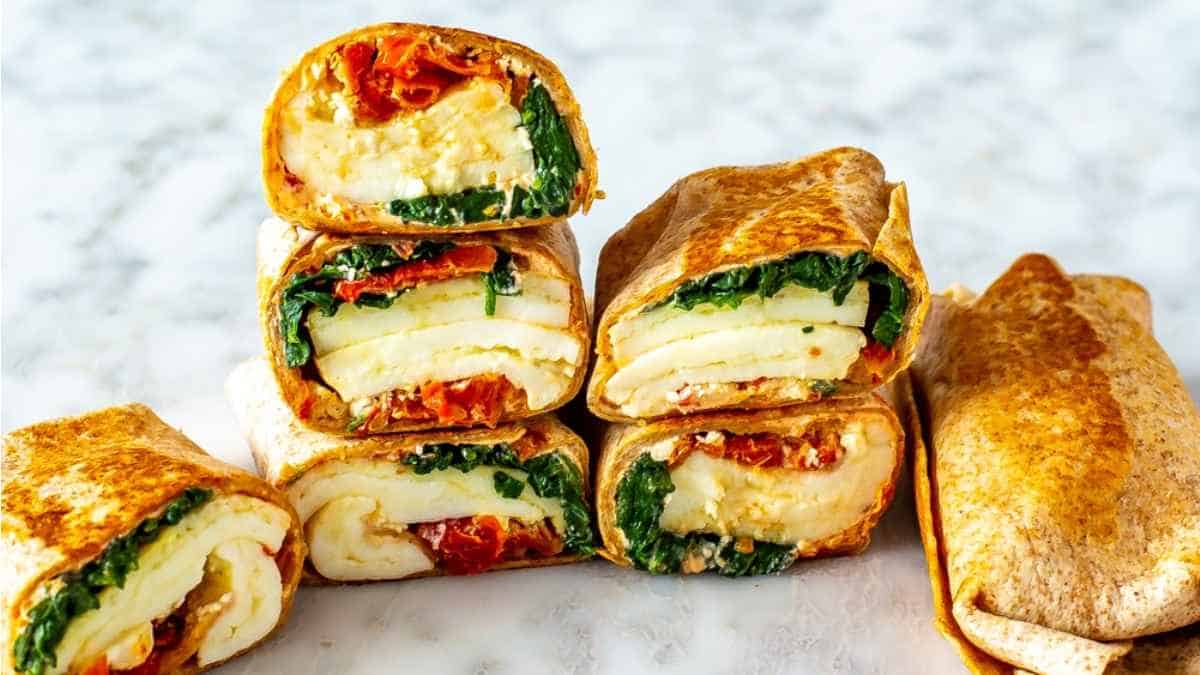 A stack of spinach and egg wraps on a marble countertop.