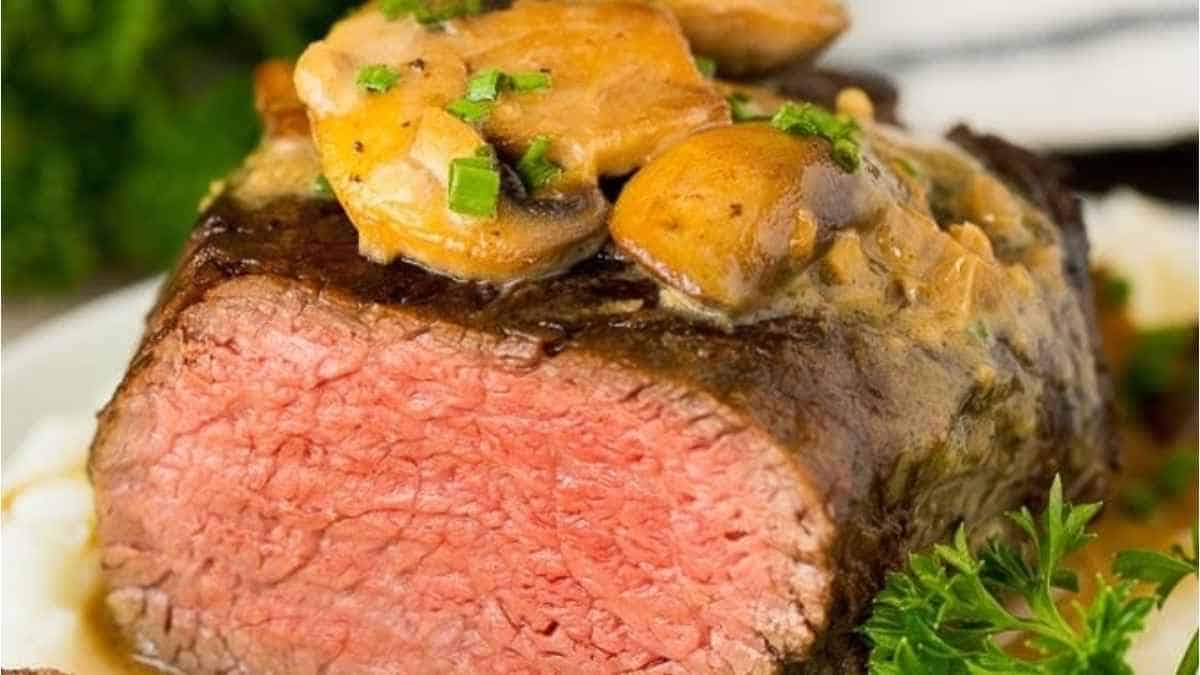 A steak with mushrooms and gravy on a plate.