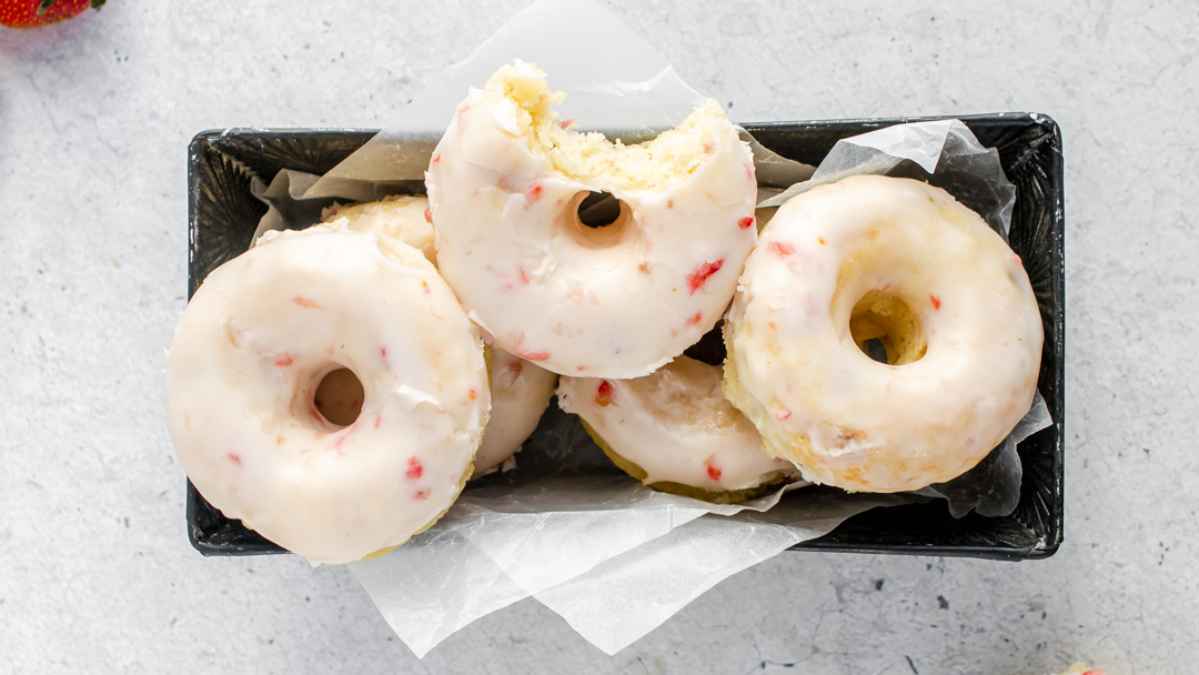 A tray of doughnuts with white frosting.