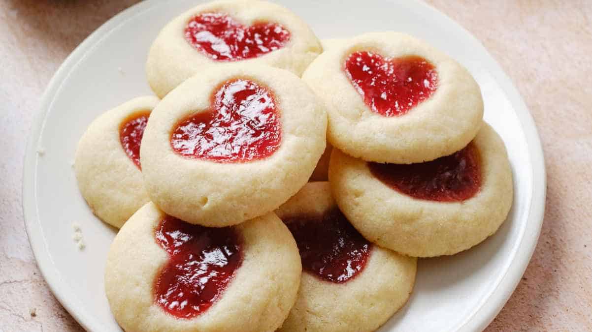 A plate of cookies with jam in the shape of a heart.