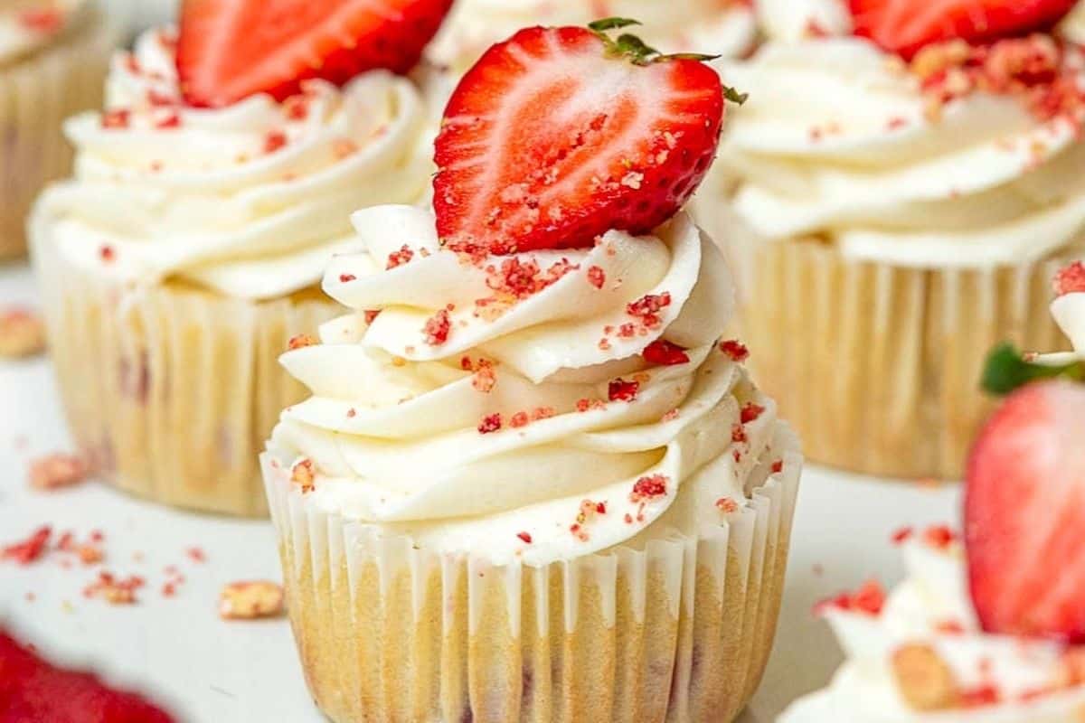 Vanilla cupcakes with cream frosting and fresh strawberry garnish.