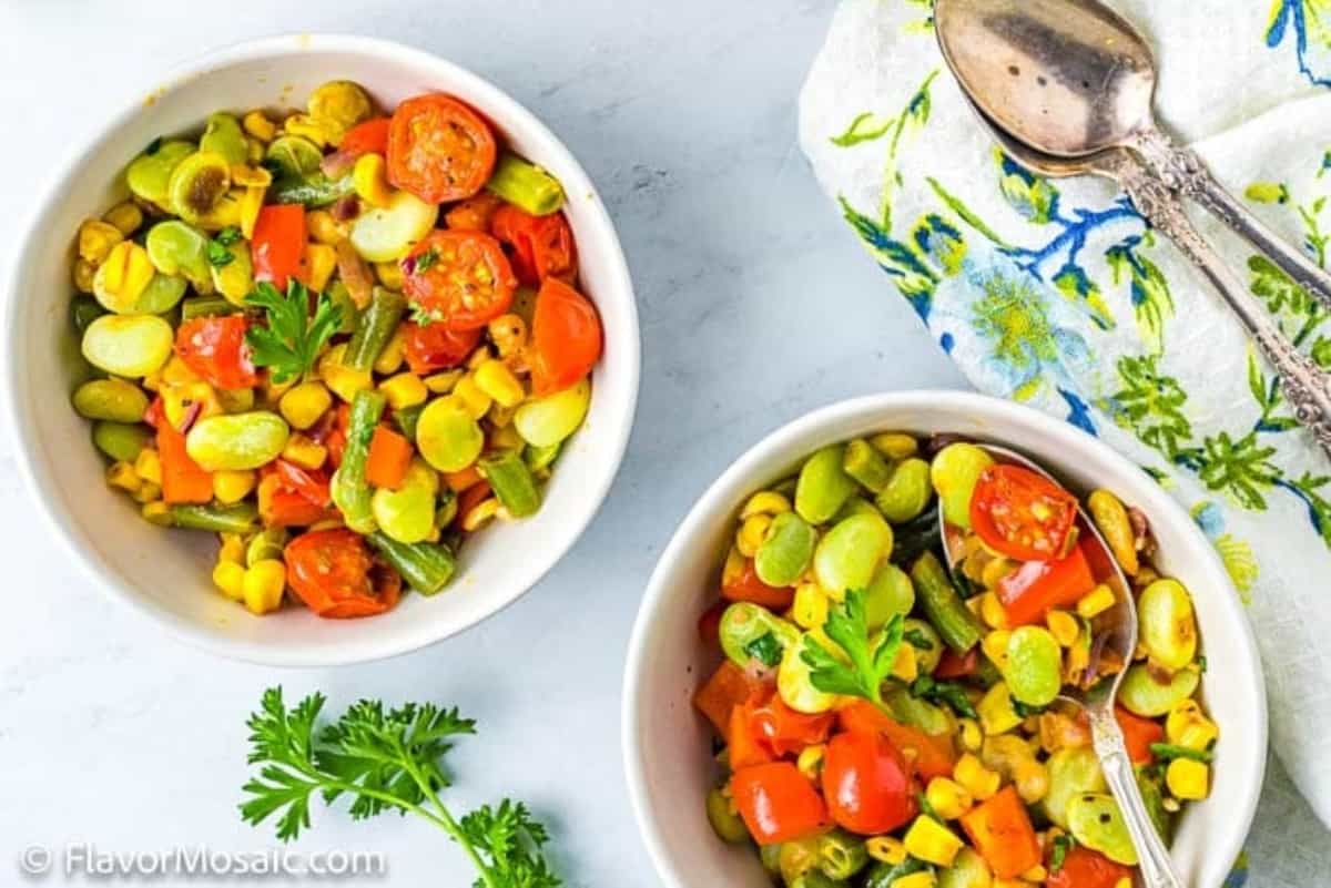 Two bowls of vegetable salad on a table.